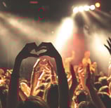 a person holding a heart shaped hand gesture with their hands at a concert