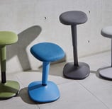 Upholstered motion stools in blue, grey, green with rounded seats and weighted bases
