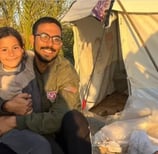a man and a little girl are sitting in front of a tent