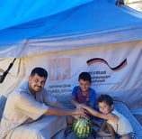 a man and two children sitting on a picnic table