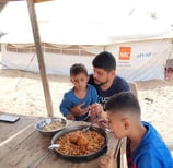a man and two boys eating food at a table