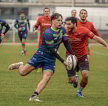 Joueur de rugby qui court et va faire une passe avant de se faire plaquer.