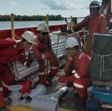 a group of people in red suits and white helmets on a boat