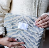 Trousse de toilette ÉTOFÉ en tissu d’ameublement revalorisé beige et bleu, tenue à la main