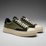 Sepatu kets pria dari kanvas hijau army dengan aksen hitam dan sol putih.