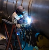 a man welding a pipehead in a factory