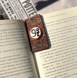 brick wall textured bookmark with platform 9 3/4 sign on the center displayed on a harry potter book