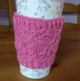 a cup of coffee with a pink cup cosy