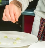 uno chef che condisce il suo piatto