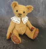 a handmade teddy bear wearing a lace collar