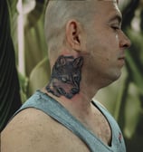 a man with a wolf tattoo on his neck