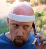A man in workout attire listens to a call on his outdated cell phone