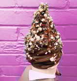 une glace a l'italienne trempée dans du chocolat fondant avec des éclats de cacahuètes 