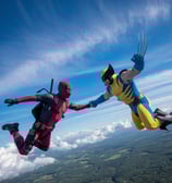 deadpool and wolverine hodling hands while sky diving