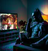 sad batman crying watching a romantic movie while eating popcorn
