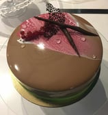 a cake with a pink and brown cake on top of a glass plate