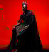 a black man with a crown and capelet dress