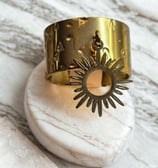 a gold cuff bracelet with a sunflower on it