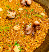 a pan of food with rice paella and octopus tentacles