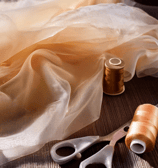 layers of sheer peach and creamy brown fabric with matching thread