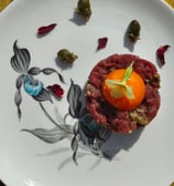 Venison tartar with an egg yolk, primrose garnish, dandelion capers and rose petals