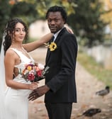 A Bedfordshire bride and groom smile for a photo, surrounded by ducks in a picturesque outdoor setting