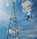 Drone voert visuele inspectie uit bij hoge zendmast onder een heldere hemel