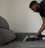 a man is cleaning a couch with a vacuum