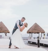 a bride and groom kissing on a pier