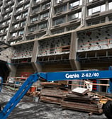 a crane lifts a load of wood to a building