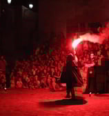un uomo con mantello nero che inizia lo spettacolo firestorm con un fumogeno rosso