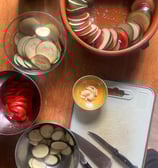 a table with bowls of sliced vegetables and a knife