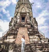 a woman standing in front of a temple with a sky background
