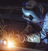 a man in a welding helmet welding a piece of metal