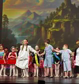 a group of children and adults in costume on stage