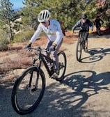 two people riding bikes on a dirt road