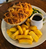 a pie with a mug of gravy and some chips