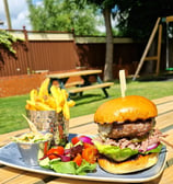 a hamburger and fries with salad in a beer garden