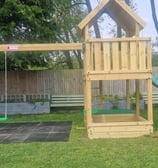 a wooden swing set with a slide in a beer garden