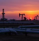 a sunset over a large oil rig with oil pumps