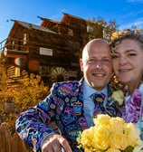 a man and woman standing in front of a wooden house