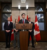 a man in a suit and tie standing at a podium with two other people