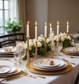 A gorgeoues aesthetic tablescape with gold taper candle holders, white china, and gold flatware
