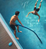 A man saving another man drowning in a swimming pool