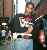 a man in a black shirt and jeans standing on a city street