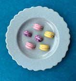 colorful polymer clay half macaron shaped fridge magnets displayed on pastel blue plate 