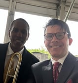 Trombonist Vincent Gardner and trumpeter George Chase smile for the camera at a performance.