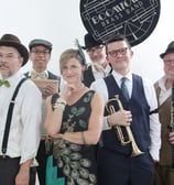 Promotional picture of Boomtown Brass Band, with trumpeter and other musicians in period clothing
