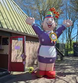 Opblaaspop Sarah, Feestelijke muts op aan de voorkant van een restaurant. Gekleed in Paarse jurk