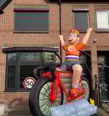 Oblaasbare wielrenner met oranje shirt en Nederlandse vlag zitten op een rode racefiets